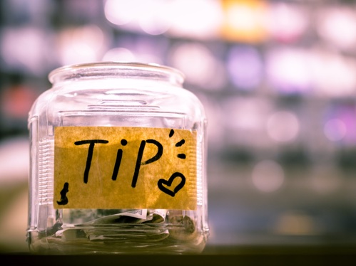 A glass jar with tip written on it