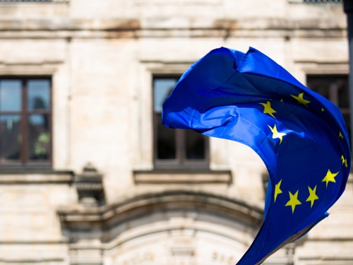 A European Union flag flying in front of a building