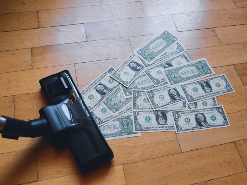 A vacuum cleaner sucking up one dollar bills