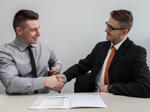 Two men shaking hands over a document