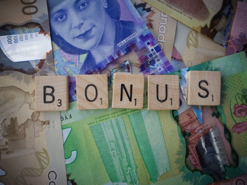 Letters spelling bonus placed on paper money bills