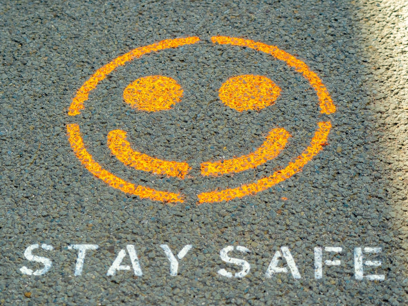A smiley and the words "stay safe" written on a road
